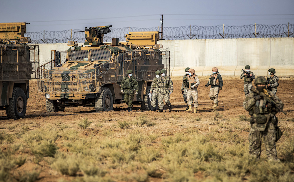 Russian and Turkish soldiers walk together while clad in surgical masks due to the COVID-19 coronavirus pandemic during a joint Russian-Turkish military patrol in the countryside near Darbasiyah along the border with Turkey in Syria's northeastern Hasakah province on November 30, 2020. (AFP/File Photo)