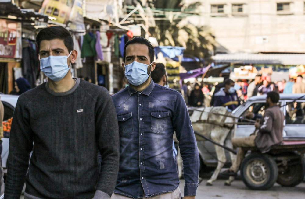 Palestinian men wear protective face masks in Rafah, Gaza Strip, on Dec. 10, 2020. An Egyptian security delegation visited Gaza on Thursday to hold talks with the leadership of Hamas. (AFP / SAID KHATIB)