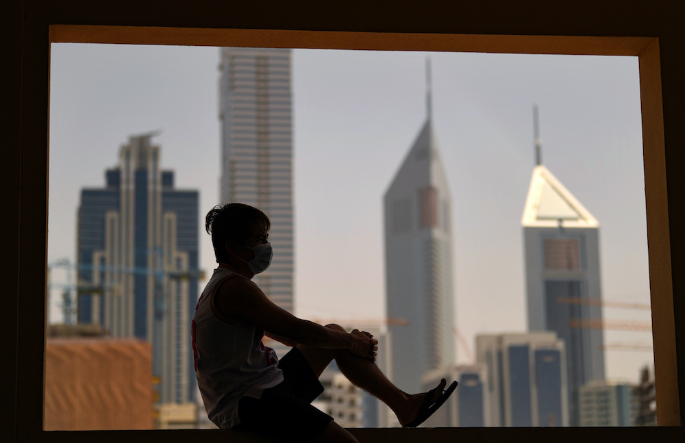 A man wearing a face mask gazes at the Dubai skyline from a window, during a lockdown imposed by the authorities in a bid to slow down the spread of the novel coronavirus in the Emirati city on April 5, 2020. (AFP/File Photo)