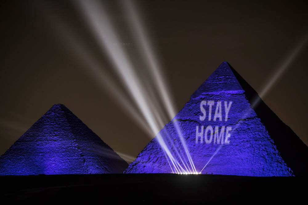 A picture taken on April 18, 2020 show the Great pyramids lighten-up with blue light and reading with a laser projection the message "Stay Home" on the Giza plateau outside the Egyptian capital of Cairo, on the world heritage day, as the country fights against the spread of COVID-19. (AFP/File Photo)