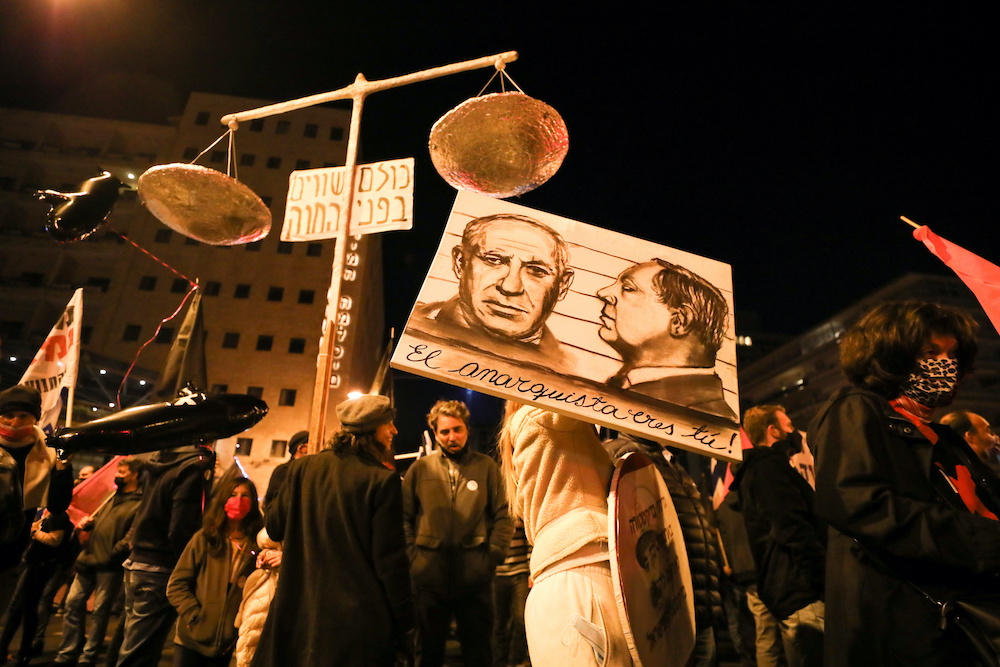 People take part in a protest against Israeli Prime Minister Benjamin Netanyahu’s alleged corruption and his handling of the coronavirus disease (COVID-19) crisis, in Jerusalem, Jan. 9, 2021. The painting reads “The anarchist is you. (Reuters)