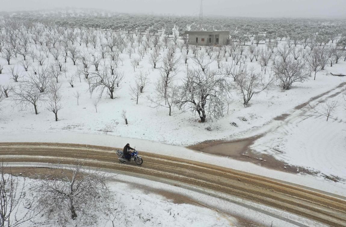 A Syrian man rides a motorcycle among groves covered with snow in the Jabal al-Zawiya region in the rebel-held northern countryside of Syria's Idlib province, on February 17, 2021. (AFP)