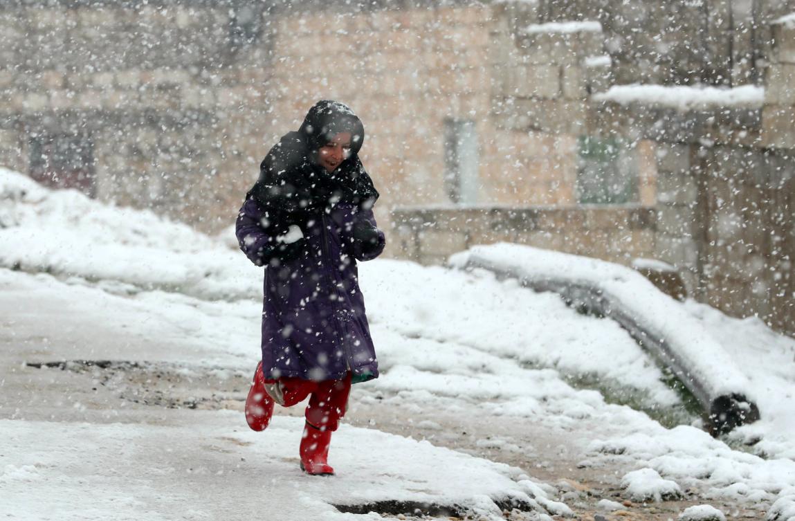 A young Syrian girl runs on a snow-covered street in the Jabal al-Zawiya region in the rebel-held northern countryside of Syria's Idlib province, on February 17, 2021. (AFP)