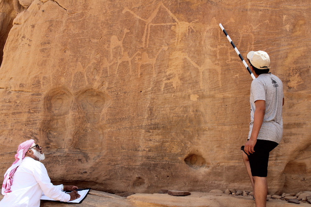 An AlUla resident and his son, trained through the Royal Commission for AlUla, work to record rock art from all eras in the Rukab Mountains. (Supplied)