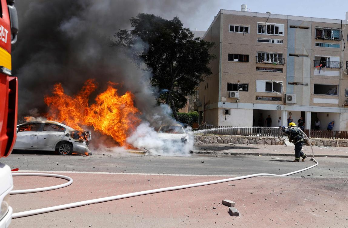 Israeli firefighter extinguishes a burning vehicle on Tuesday after Hamas launched rockets from Gaza Strip to Ashkelon, at southern Israel. (AFP)