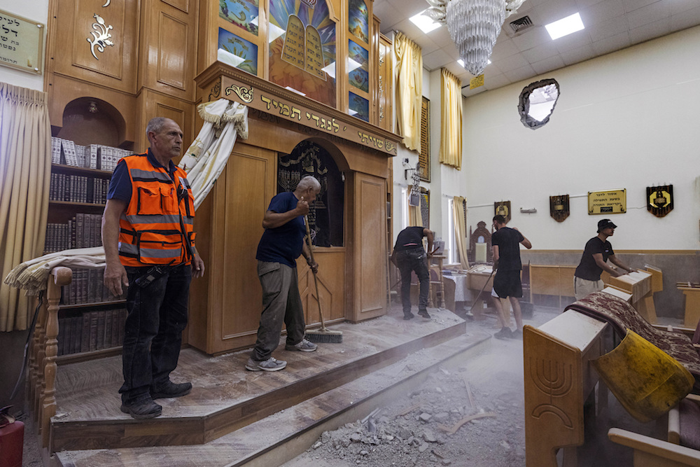 People clean a damaged synagogue after it was by a rocket fired from the Gaza Strip, In Ashkelon, Israel, Sunday, May 16, 2021. (AP)