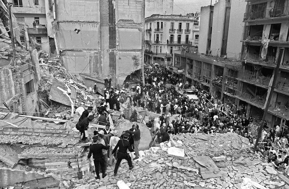 Firemen and policemen search for wounded people after a bomb exploded at the Argentinian Israelite Mutual Association (AMIA in Spanish) in Buenos Aires, 18 July 1994. 85 people died in the attack. (AFP/File Photo)