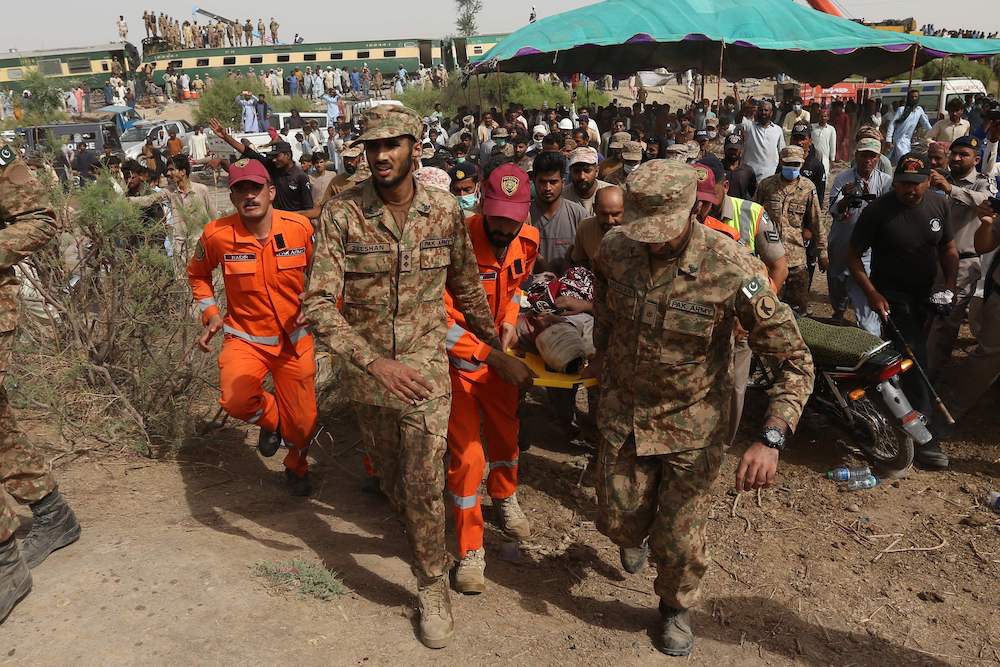 Security personnel carry an injured passenger to an army helicopter at the site of a train accident in Daharki area of the northern Sindh province on June 7, 2021. (AFP)