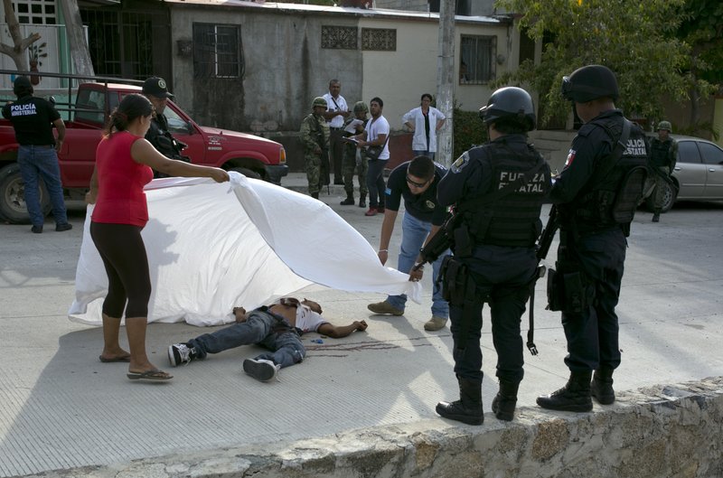 A forensic officer helps a woman place a sheet over the body of a victim of Mexico's unending drug war in this April 15, 2016 file photo. (AP file photo)