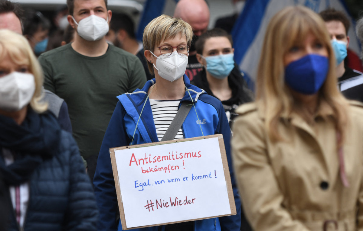 A member of the Initiative against Anti-Semitism Gelsenkirchen holds a placard reading 'fight antisemitism — No matter where it comes from — #never again' during a vigil in front of the synagogue in Gelsenkirchen, Germany, on May 14, 2021. (AFP)