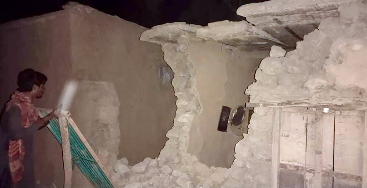 A local resident inspects his house damaged by Thursday's earthquake h in Harnai, Pakistan. (AP Photo)