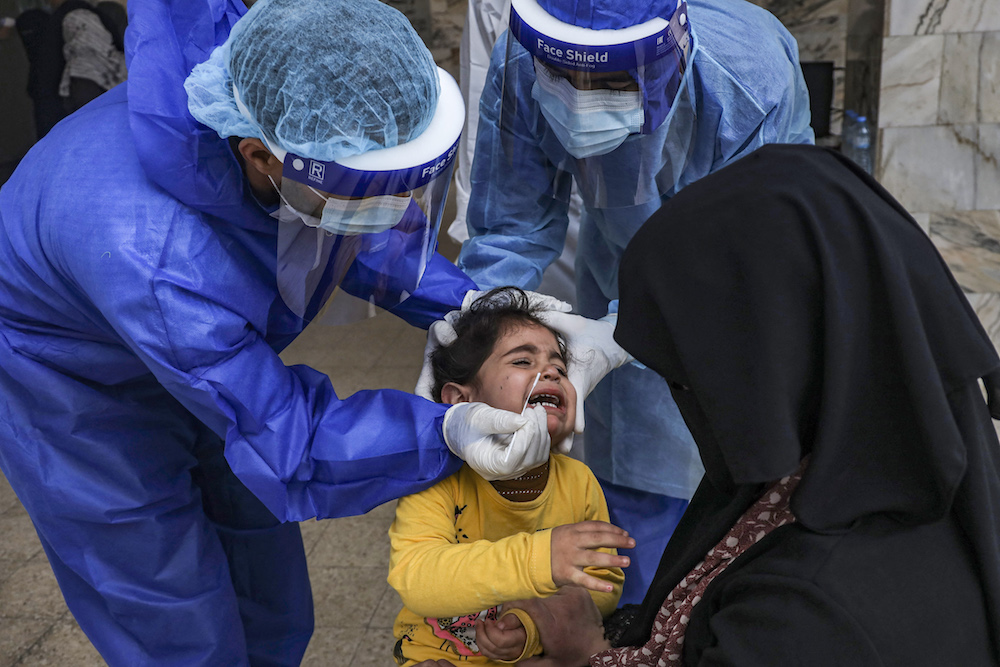 A young girl reacts as a health worker collects nasal swab sample from her at a local clinic for COVID-19 coronavirus disease testing in Gaza City. (AFP/File Photo)