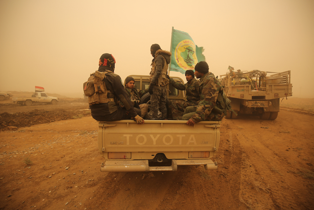 Shiite fighters from the Hashed Al-Shaabi (Popular Mobilization) paramilitaries drive through a desert area near the village of Al-Boutha Al-Sharqiyah, west of Mosul. (AFP/File Photo)