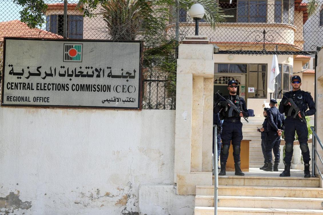 Police officers stand guard as Palestinians begin registering party lists for May parliamentary election, at the Central Elections Commission's office in Gaza City March 20, 2021. (Reuters)