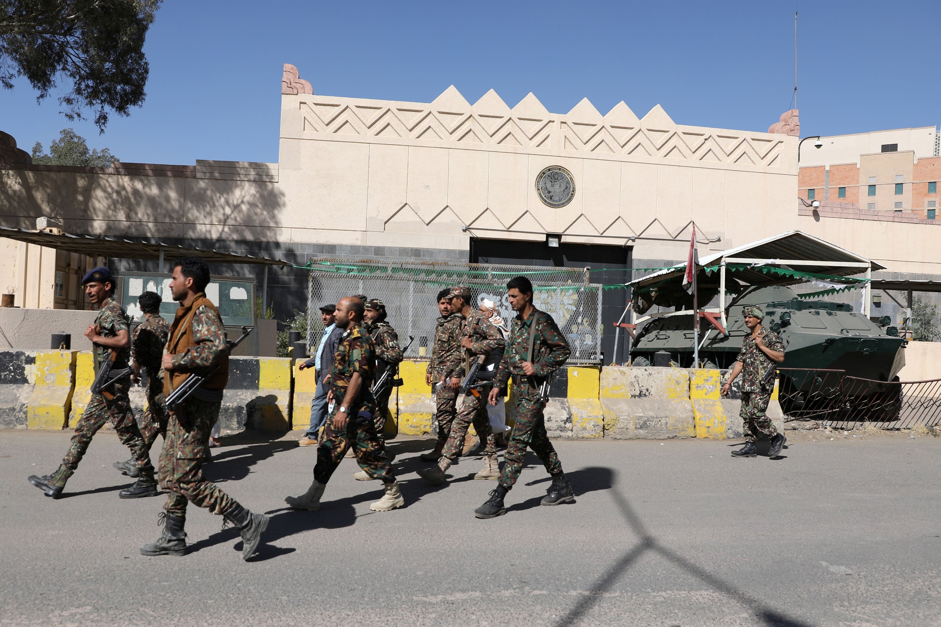 Houthi militants walk past the the US embassy’s gate in Sanaa, Yemen. (File/Reuters)