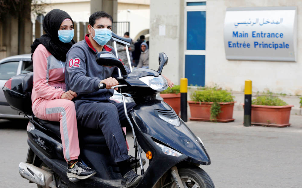 People wearing face masks ride on a motorbike outside Rafik Hariri hospital, where Lebanon's first coronavirus case is being quarantined, in Beirut, Lebanon February 21, 2020. (REUTERS)