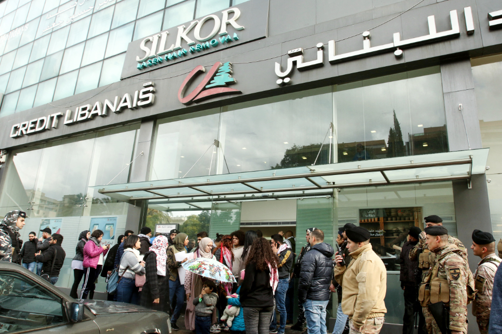 Lebanese protesters gather in front of a bank in the southern city of Sidon to protest against restrictions on dollar withdrawals and transfers abroad. (File/AFP)