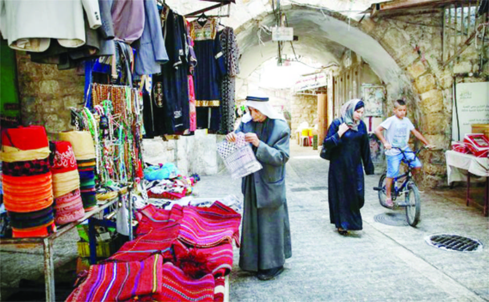 A Palestinian man browses merchandise as another woman walks by in an alley in the old market of the divided West Bank city of Hebron. (AFP file photo)