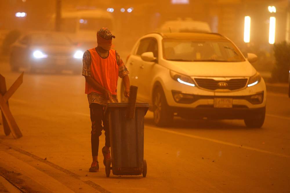 An Iraqi cleaner works to clean the street during a severe dust storm in the Iraqi capital Baghdad on May 1, 2022. (AFP)