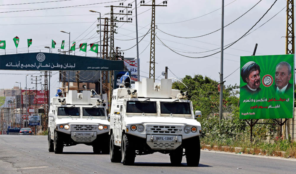 UNIFIL vehicles drive past Lebanese parliamentary election billboards on a highway in the southern city of Tyre, on May 5, 2022. (AFP)