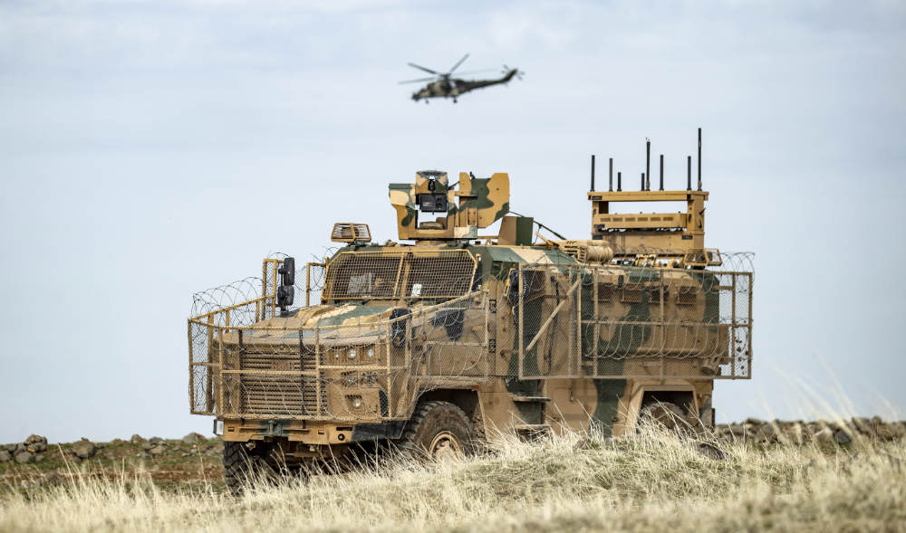 A helicopter gunship flies above a Turkish military vehicle in Syria’s northeastern Hasakeh province close to the Turkish border. (AFP file photo)