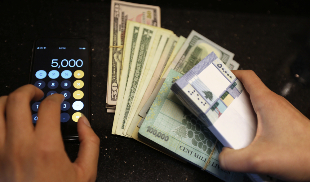 A woman counts Lebanese pound and US dollar banknotes at a currency exchange shop in Beirut, Lebanon. (REUTERS)