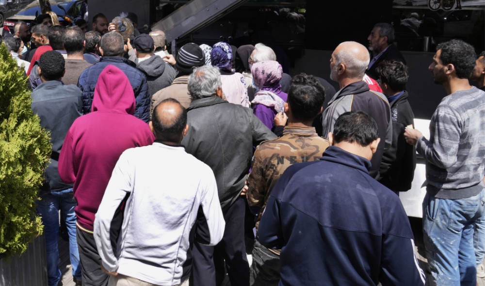 Lebanese and Syrian citizens queue for bread outside a bakery, in the southern suburb of Beirut, Lebanon, Tuesday, April 12, 2022. (AP)