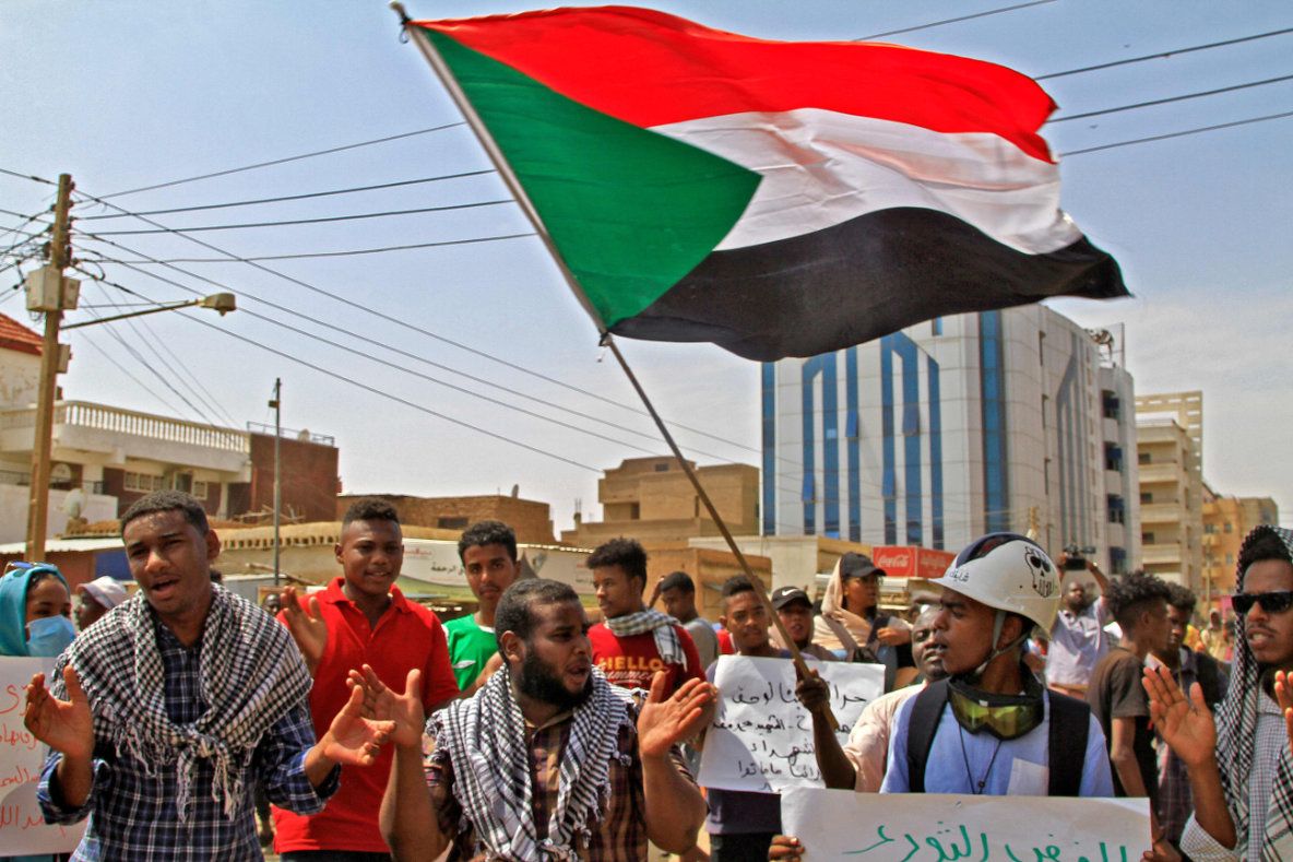 Sudanese demonstrators lift national flags and placards during a rally to demand the return to civilian rule, in the Bashadar station area of the the capital Khartoum, on September 13, 2022. (AFP)