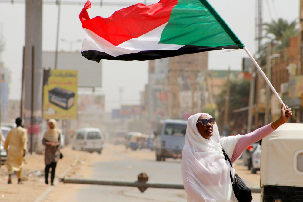 A Sudanese anti-coup protester waves a national flag as people take to the streets of the capital's northern district of Khartoum-Bahri, on September 17, 2022. (AFP)
