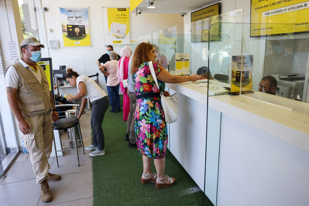 Employees serve customers at a money transfer office in Lebanon's capital Beirut, on July 27, 2022. (AFP)