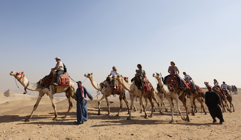 Tourists ride camels in front of the Great Pyramids plateau in Giza, Egypt December 11, 2022. (REUTERS)