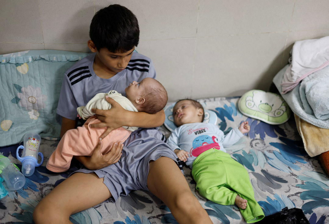 Displaced Palestinian boy looks after his twin siblings as they take shelter at Nasser hospital in Khan Younis, Gaza Strip.