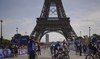 Cyclists arrive by the Eiffel Tower, ahead of the start of the women's road cycling event, at the 2024 Summer Olympics, Sunday, 