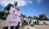 A man holds a placard during a demonstration on the opening day of Sudan ceasefire talks, in Geneva, on August 14, 2024. (AFP)