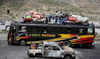 A bus drives past a damaged vehicle, a day after separatist militants conducted deadly attacks, in Balochistan.