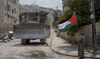 A man waves the Palestinian flag as a convoy of Israeli military bulldozers drive by during an army raid in Jenin, West Bank.