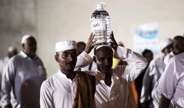 Departing pilgrims face cap on Zam Zam water