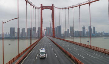 In this Jan. 25, 2020, file photo, an ambulance drives across a nearly empty bridge in Wuhan, China, after the city was placed under a 76-day lockdown amid a rising COVID-19 outbreak. China managed to place the contagion under control early while other countries continue to suffer from the pandemic one year after. (Chinatopix via AP, File)