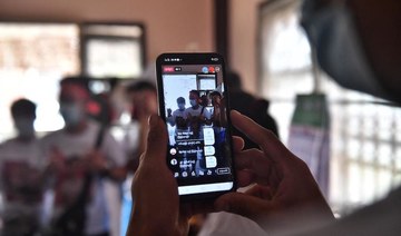 Myanmar migrants sharing their activities on social media before going to a local protest against the military coup in their home country, at a house in the outskirts of Bangkok (AFP)