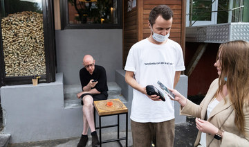 A waiter serves customers outside the Moments bar as they haven't got QR codes of vaccination or a negative coronavirus test in Moscow, Russia, Monday, June 28, 2021. (AP)