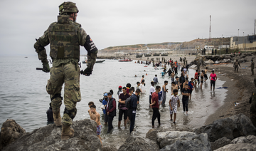 People mainly from Morocco stand on the shore as the Spanish Army cordons off a beach at the border of Morocco and Spain in the Spanish enclave of Ceuta on May 18. (AP/File Photo)