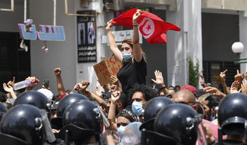 A Tunisian protester lifts a national flag at an anti-government rally as security forces block off the road in front of the Parliament in the capital Tunis on July 25, 2021. (AFP)