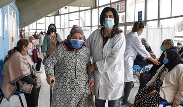 A medical worker assists an elderly woman arriving to receive a dose of vaccine (AFP/File Photo)