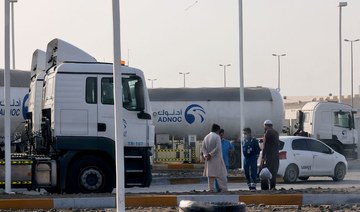 Men stand outside a storage facility of ADNOC in Abu Dhabi, on Jan. 17, 2022. Three people were killed in a suspected drone attack on ADNOC facilities on Monday. (AFP)