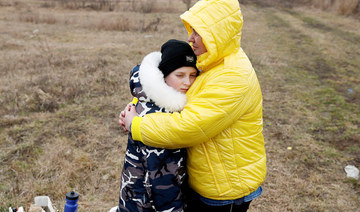 Nataliya Ableyeva, 58, comforts a child who was handed over to her at the Ukrainian side of the border by a father who was not allowed to cross at a border crossing in Beregsurany, Hungary, February 26, 2022. (REUTERS)