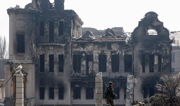 A service members of pro-Russian troops stands near a building burnt during Ukraine-Russia conflict in the southern port city of Mariupol. (Reuters)