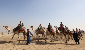 Tourists ride camels in front of the Great Pyramids plateau in Giza, Egypt December 11, 2022. (REUTERS)