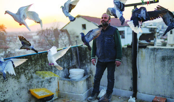 Murat Guzel scatters bird food on the roof of a restaurant where he worked before the earthquake in Antakya. (AFP)