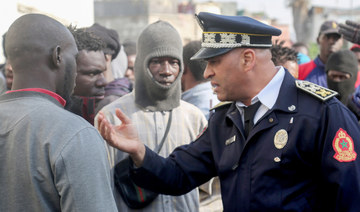 A Moroccan policeman speaks with a group of African migrants in Casablanca. (File/AFP)