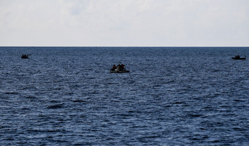 Chinese coast guard personnel (C) aboard their rigid hull inflatable boat observing Philippine coast guard personnel.